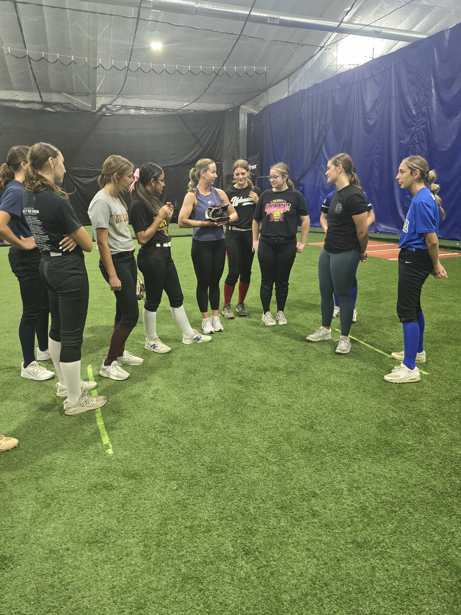 Players gathered in a circle while Jessie Harper demonstrates with a glove