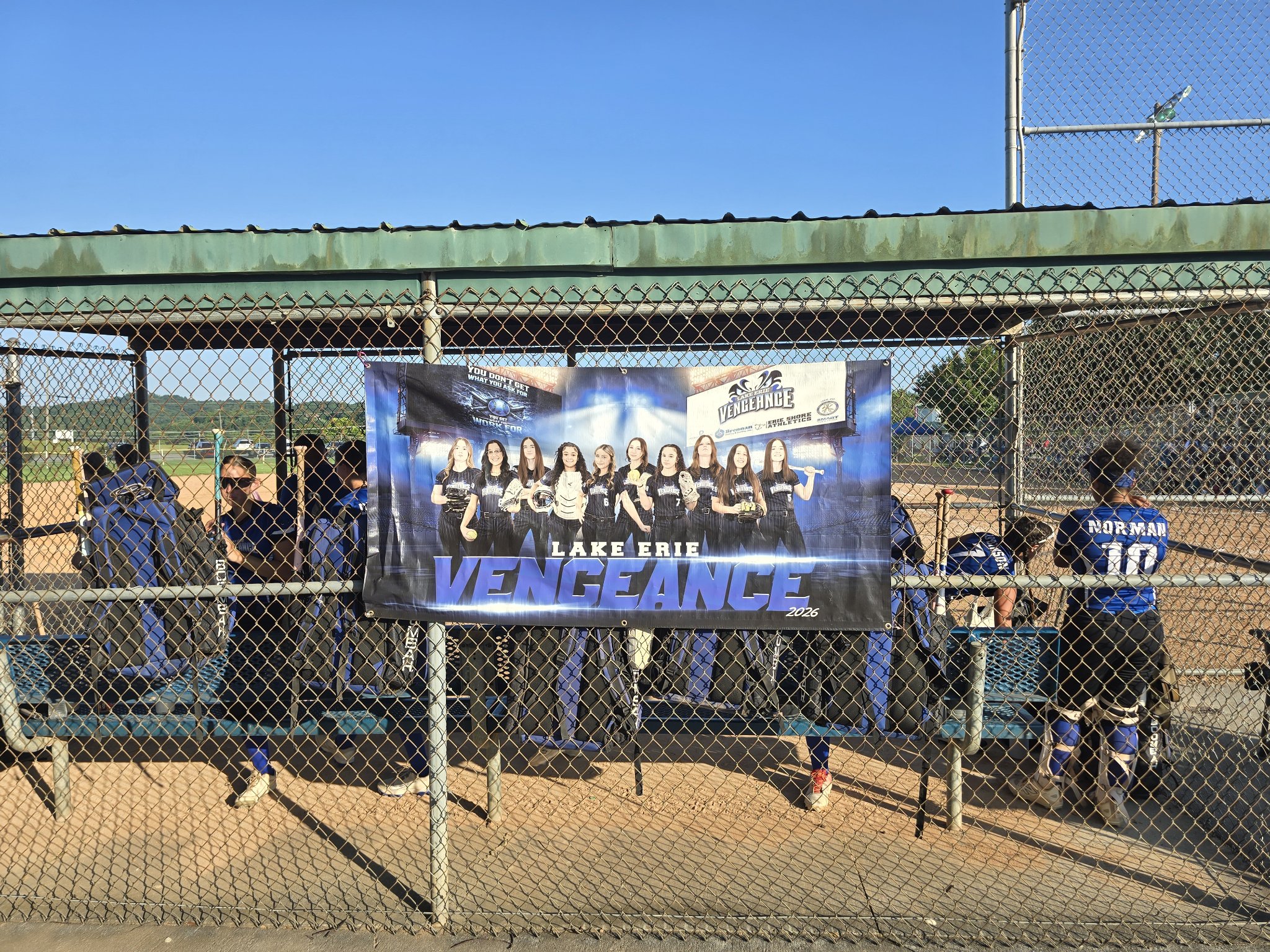 Lake Erie Vengeance team banner hanging on the chain-link dugout fence at the softball field